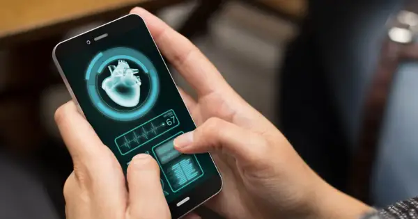 Dłoń trzyma smartfon z aplikacją zdrowie, wyświetlającą obraz serca i tętno 67.