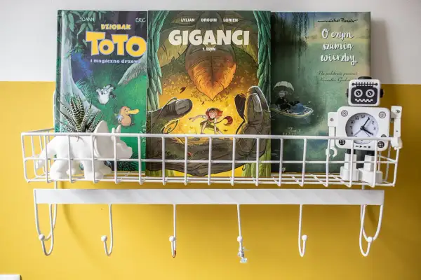 Na półce stoją komiksy dla 6 latka: "Toto i magiczne drzewo", "Giganci" i "O czym szumią wierzby". Obok robot-zegarek.