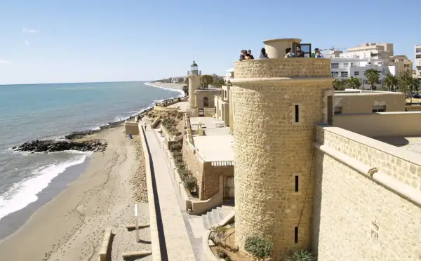 Torreón y faro en el **puerto de Roquetas de Mar**, con playa y mar Mediterráneo al fondo.