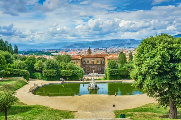 Vista panoramica dei Giardini di Boboli con stagno, palazzo e Firenze sullo sfondo.