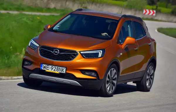 Pomarańczowy Opel Mokka 2015 na zakręcie drogi.