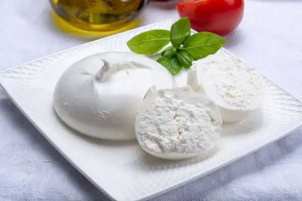 Burrata fresca su piatto bianco, con pomodoro, basilico e olio d'oliva, perfetti burrata ingredienti per un piatto estivo.