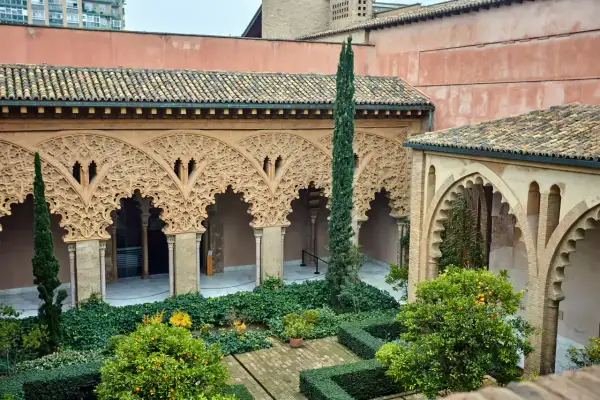 Patio de la casa de los Morlanes con arcos de yesería intrincada, vegetación exuberante y naranjos cargados de frutos.