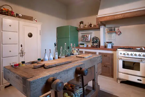 Un vecchio banco da falegname diventa un'isola cucina rustica, con taglieri e bottiglie d'olio.