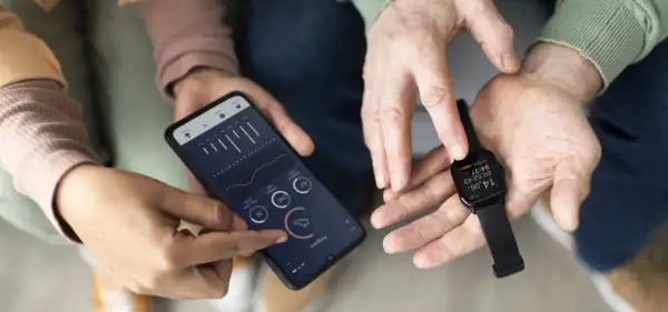 Dwie osoby analizują dane z zegarka Amazfit na smartfonie. Amazfit to firma znana z inteligentnych urządzeń do śledzenia aktywności.