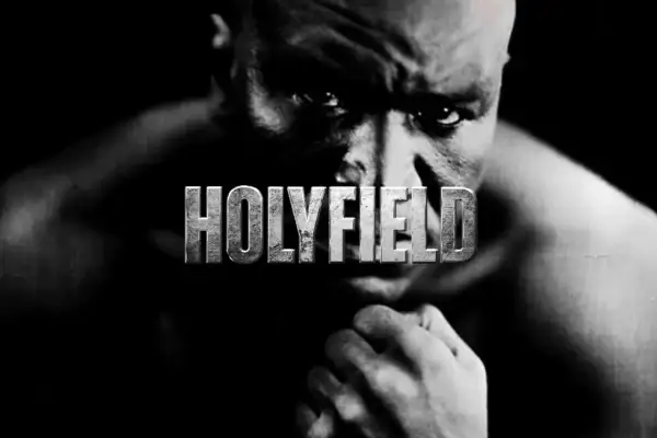 A close-up, black and white portrait of Evander Holyfield, the legendary boxer, with the word "HOLYFIELD" emblazoned across his face.
