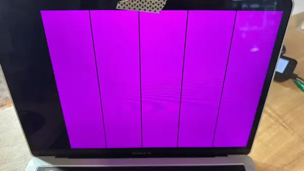Uszkodzony ekran MacBook Pro wyświetla pionowe fioletowe pasy.