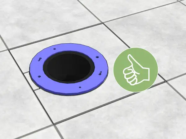 A toilet flange sits on tiled flooring, showing how to cut tile around toilet for a perfect fit. A green thumbs-up icon indicates success.