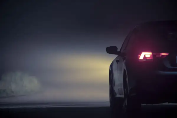 Vue arrière d'une voiture dans le brouillard, feux arrière allumés. L'emplacement des feux de voiture est bien visible.