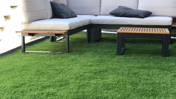 Sofá moderno y mesa auxiliar sobre césped artificial. ¿Cuánto cuesta poner césped natural?