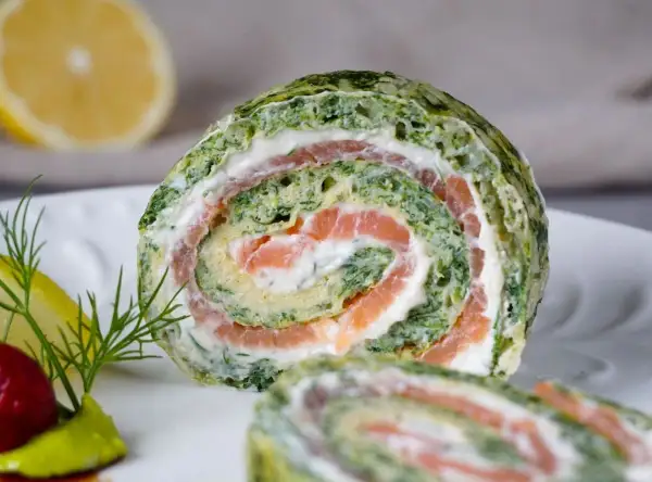 Ein saftiger Spinat Lachs Rolle auf einem Teller, garniert mit Dill und Zitrone.
