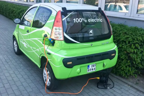 Zielony elektryczny samochód ROMET HE z napisem "100% electric" jest ładowany. To część programu "Mój Elektryk".