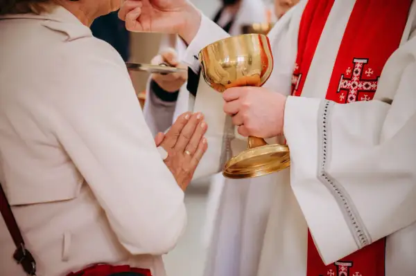 Kapłan podaje kielich podczas komunii. Czy po spowiedzi trzeba przyjąć komunię? To ważny moment duchowy.
