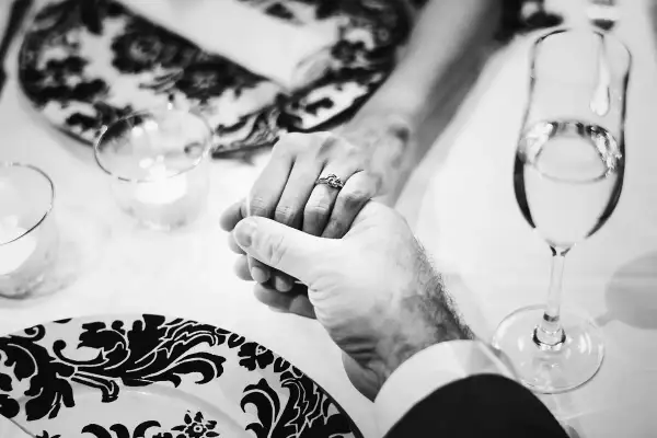 Mani intrecciate, un anello che simboleggia 40 anni di matrimonio smeraldo o rubino. Brindisi con champagne per celebrare un amore duraturo.