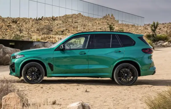 Zielony SUV, idealne ekonomiczne auto na długie trasy, zaparkowany na pustynnym tle z nowoczesnym budynkiem w tle.