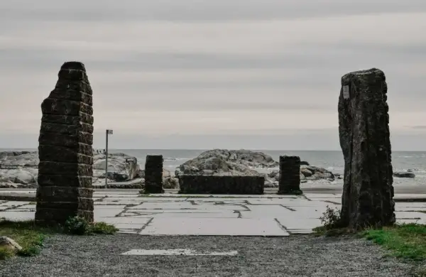 Kamienne filary i kamienna ława na placu przy morzu, jakby na **verdens ende**.