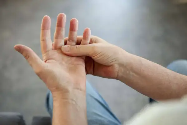 Person massiert Hand, da die Finger schmerzen beim Beugen.