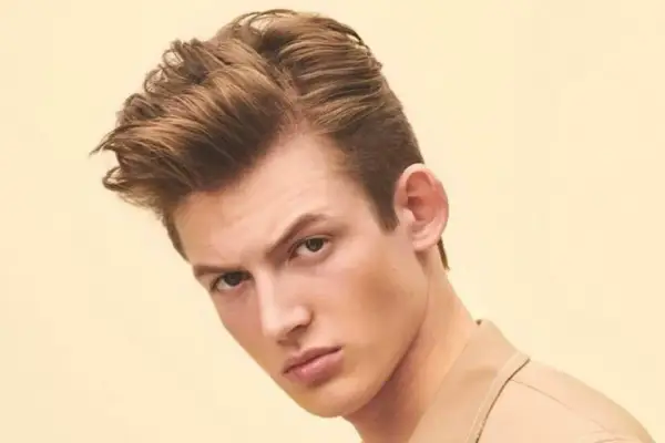 Un jeune homme arbore une coupe de cheveux homme mi long dégradé, avec du volume sur le dessus et des côtés plus courts.