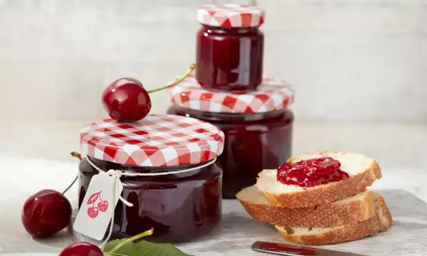 Gläser mit kirsch marmelade, frische Kirschen und Brot mit Marmelade.