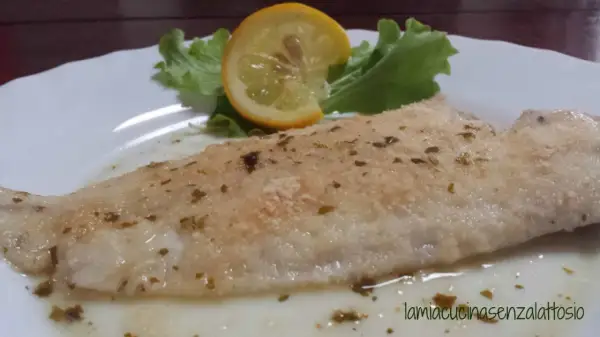 Sogliola al forno con panatura croccante, guarnita con una fetta di limone e insalata fresca. Un piatto leggero e gustoso.