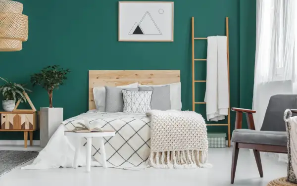 Chambre parentale cosy aux murs vert émeraude, lit en bois, plaids douillets et plantes vertes pour une ambiance relaxante.