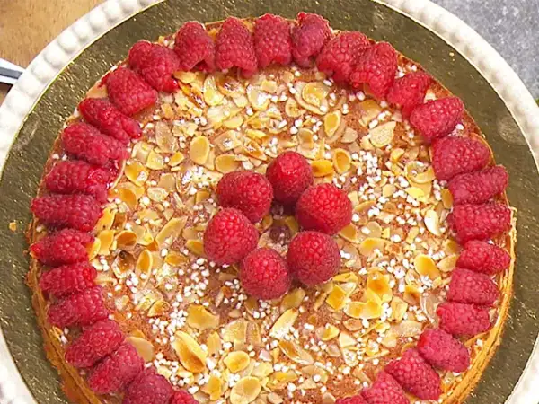 En vacker mandelkaka med citron, toppad med färska hallon och mandelflagor. En härlig sommartårta!