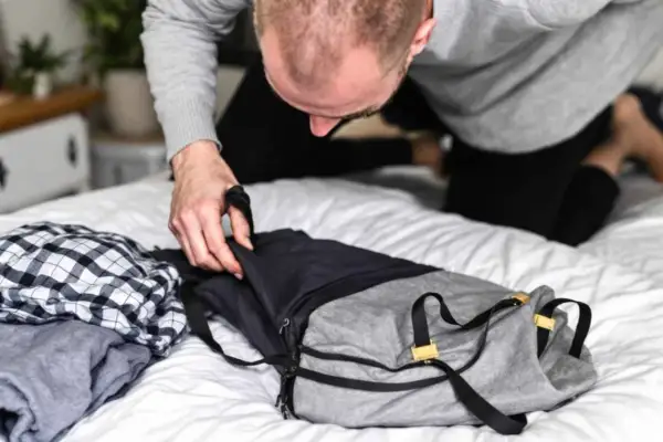 Un homme prépare son sac. Il se demande combien de kilo dans un sac de 30l peut contenir pour son voyage.