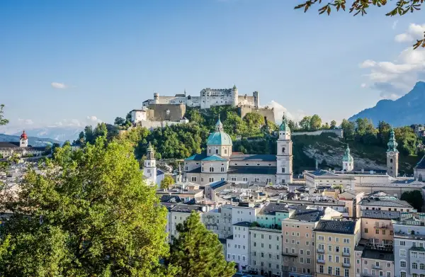 Widok na zamek Hohensalzburg i katedrę w Salzburgu, serce ziemi salzburskiej, z zielonymi drzewami w tle.