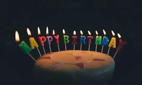 Płonące świeczki w kształcie liter tworzą napis "Happy Birthday". Idealne na życzenia urodzinowe po angielsku.