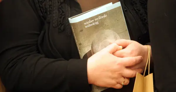 Dwie osoby trzymają książkę "Widnokrąg" Wiesława Myśliwskiego.