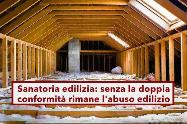 Sottotetto in costruzione, con travi in legno e isolamento. La scritta "Sanatoria edilizia: senza la doppia conformità rimane l'abuso edilizio" evidenzia un problema legale.