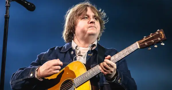 Lewis Capaldi gra na gitarze, mimo swojej choroby, z pasją i zaangażowaniem.