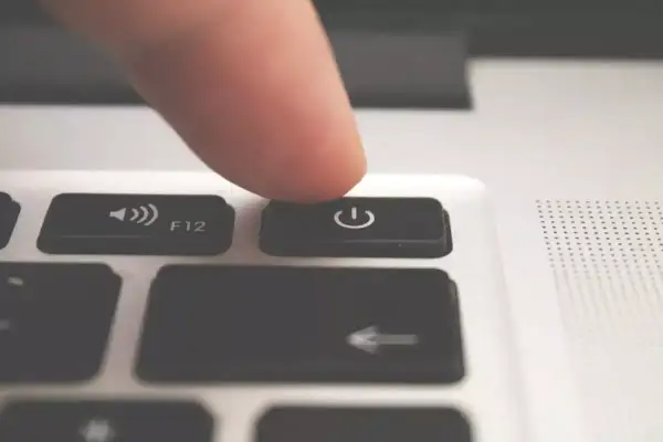 Palec naciska przycisk zasilania, planując automatyczne wyłączanie komputera Windows 10.