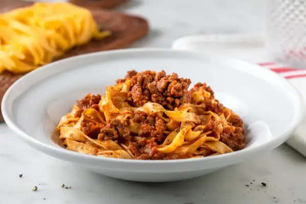 Tagliatelle al ragù, un classico delle ricette italiane, servite in un piatto bianco.