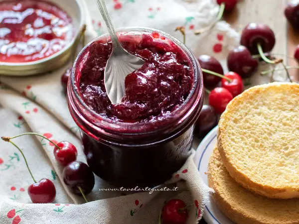 Un barattolo pieno di deliziosa marmellata di ciliegie, pronto per essere spalmato su fette biscottate.