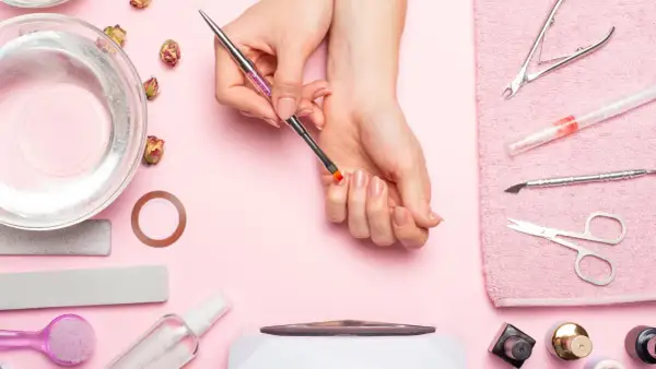 Narzędzia do manicure i dłonie przygotowujące się do zabiegu. Dowiedz się, jak zdjąć tipsy i uzyskać naturalny wygląd paznokci.