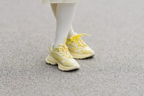 Żółte sneakersy na nogach w białych skarpetkach. Czy 36 rozmiar buta ile to cm?