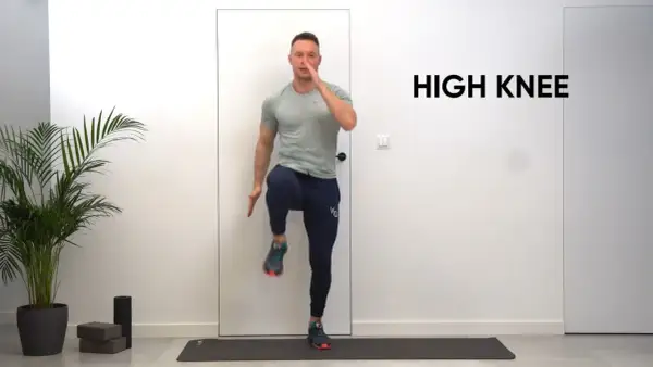 Mężczyzna wykonuje ćwiczenie high knees na macie treningowej.