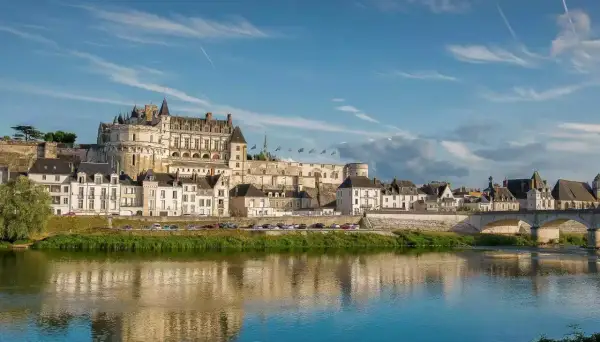 Le majestueux château d'Amboise se dresse fièrement au-dessus de la Loire, ses tours et façades blanches reflétant la lumière du soleil sur l'eau paisible.