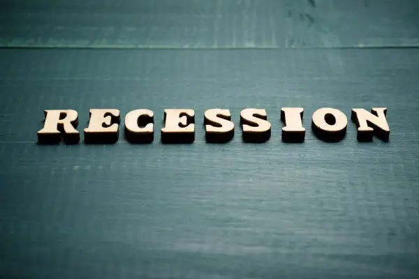Drewniane litery układają napis "RECESSION". To słowo często pojawia się, gdy zastanawiamy się, co to znaczy recesja i jak wpływa na gospodarkę.