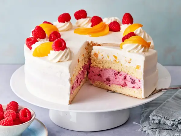 Eine köstliche Pfirsich Melba Torte mit saftigen Himbeeren und Pfirsichstücken, verziert mit Sahnetuffs.