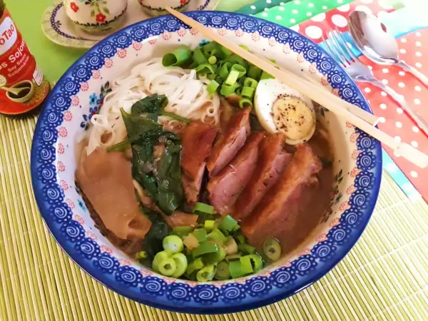 Aromaticzny ramen z kaczki z makaronem ryżowym, jajkiem na twardo, szpinakiem i szczypiorkiem.