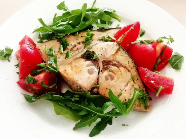 Spiedini di pesce spada in padella con pomodorini freschi e rucola, un piatto leggero e saporito.