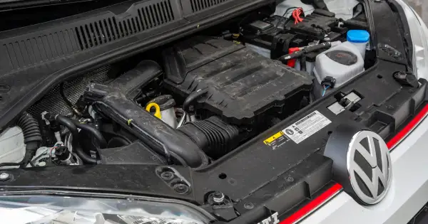 Silnik 1.0 TSI 110 KM w samochodzie Volkswagen. Widoczny akumulator, przewody i elementy osłony silnika.