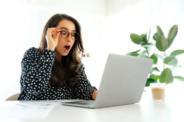 Zaskoczona kobieta odkrywa, ile dni urlopu można przenieść na następny rok, patrząc na ekran laptopa.