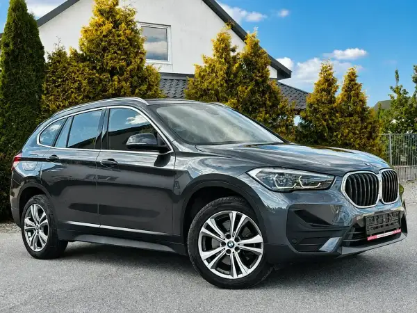 Elegancki, ciemnoszary BMW X1 na tle nowoczesnego domu. Sprawdź atrakcyjną bmw x1 cena!