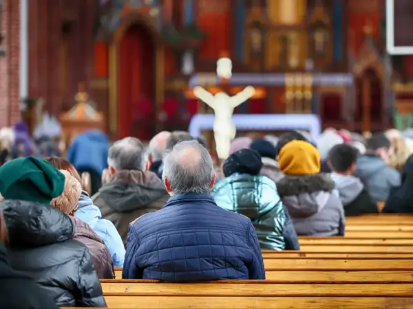 21 kwietnia. Ludzie siedzą w kościele, patrząc w stronę ołtarza z krzyżem.