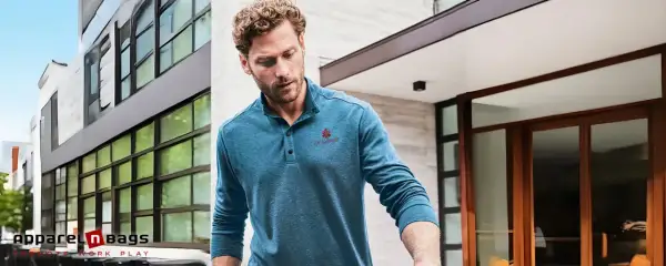 Mann trägt ein blaues Henley Shirt mit Knopfleiste und rotem Logo. Was ist ein Henley Shirt? Ein lässiges Oberteil mit Kragen und Knopfleiste.