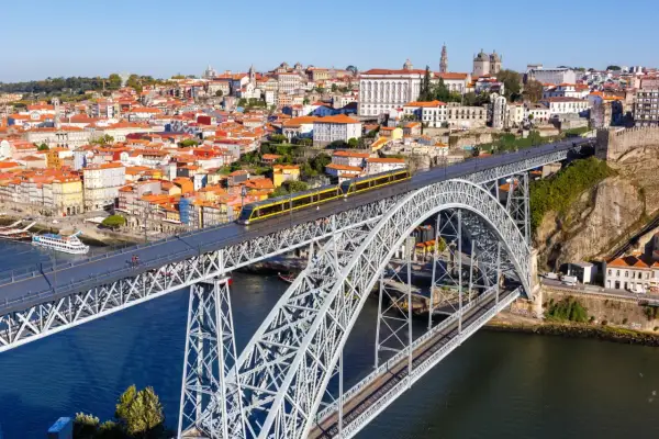 Most zwodzony w Porto z żółtym tramwajem, widok na miasto i rzekę. Szukasz informacji o wino porto cena?