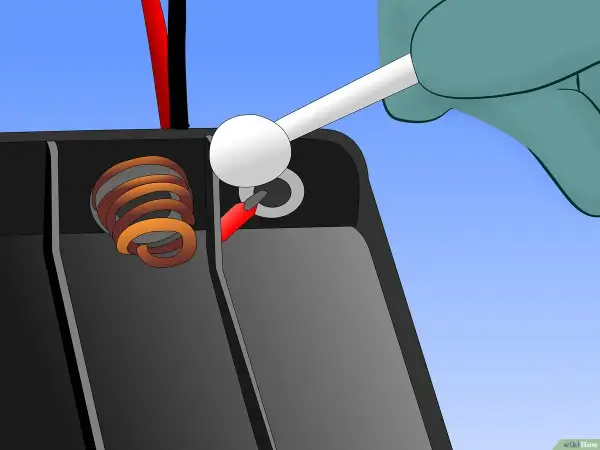 Mit einem Wattestäbchen wird die Korrosion an den Batteriepolen entfernt, um eine ausgelaufene Batterie zu reinigen.